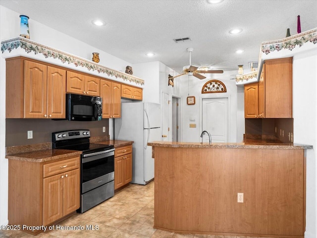 kitchen with visible vents, black microwave, stainless steel electric stove, a peninsula, and freestanding refrigerator