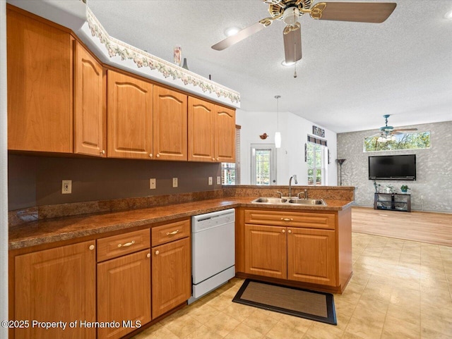 kitchen featuring a peninsula, brown cabinetry, white dishwasher, and a sink