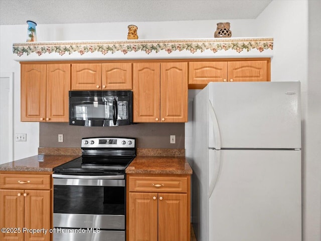 kitchen featuring stainless steel electric stove, a textured ceiling, freestanding refrigerator, and black microwave