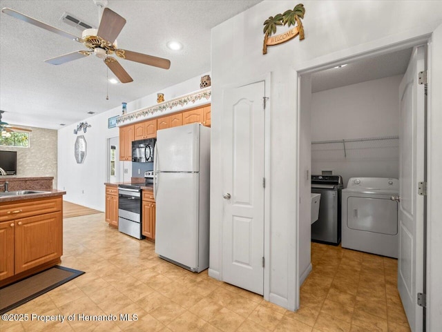 kitchen featuring visible vents, freestanding refrigerator, a sink, stainless steel range with electric stovetop, and black microwave