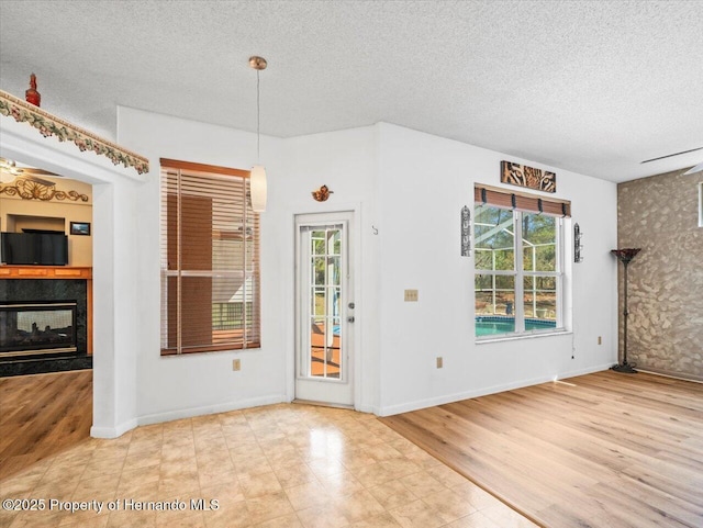 interior space featuring a multi sided fireplace, a textured ceiling, baseboards, and wood finished floors