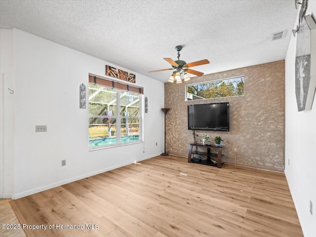 unfurnished living room with visible vents, baseboards, wood finished floors, a textured ceiling, and a ceiling fan