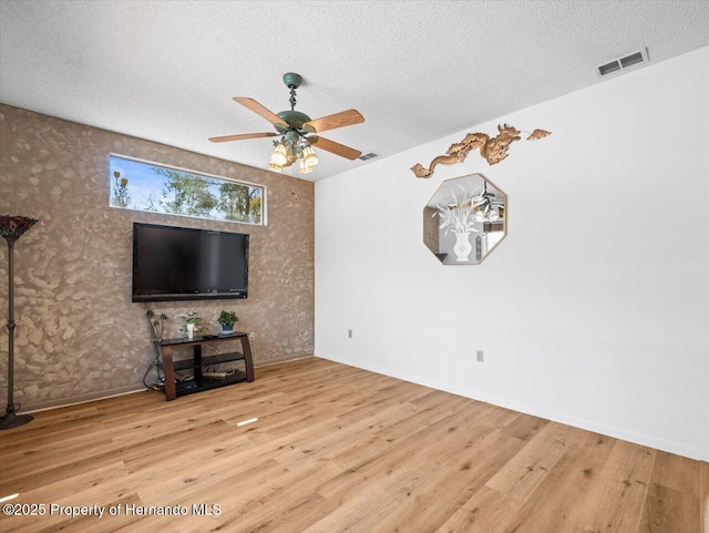 unfurnished living room featuring wood finished floors, visible vents, and a textured ceiling