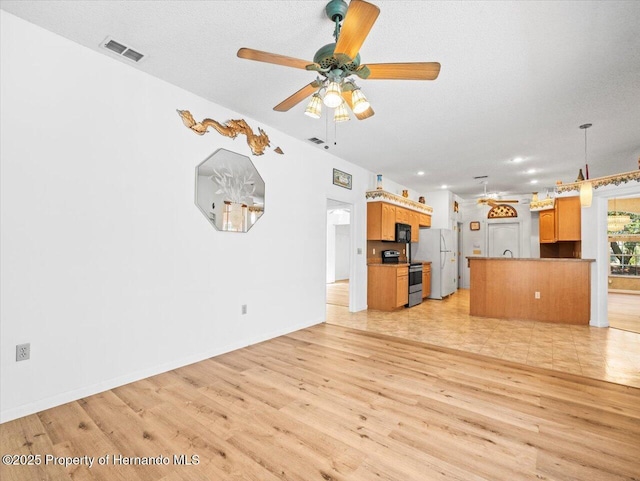 unfurnished living room featuring visible vents, light wood-style flooring, baseboards, and a ceiling fan