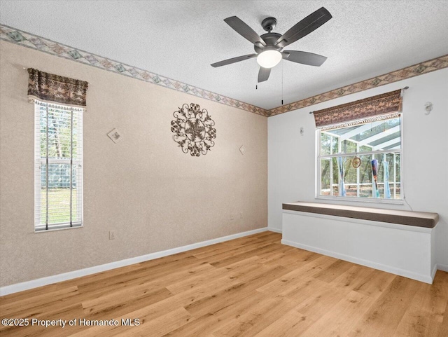 unfurnished room featuring baseboards, a textured ceiling, wood finished floors, and a ceiling fan