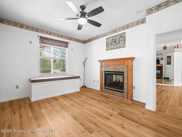 unfurnished living room featuring a fireplace, wood finished floors, baseboards, and a textured ceiling