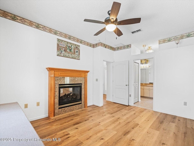 unfurnished living room featuring visible vents, a textured ceiling, light wood-type flooring, and a premium fireplace