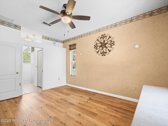 spare room featuring ceiling fan, baseboards, visible vents, and light wood-type flooring