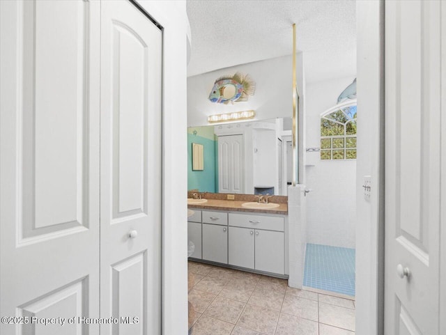 bathroom featuring tile patterned flooring, a walk in shower, vanity, a closet, and a textured ceiling