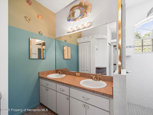 bathroom with double vanity, walk in shower, and a sink