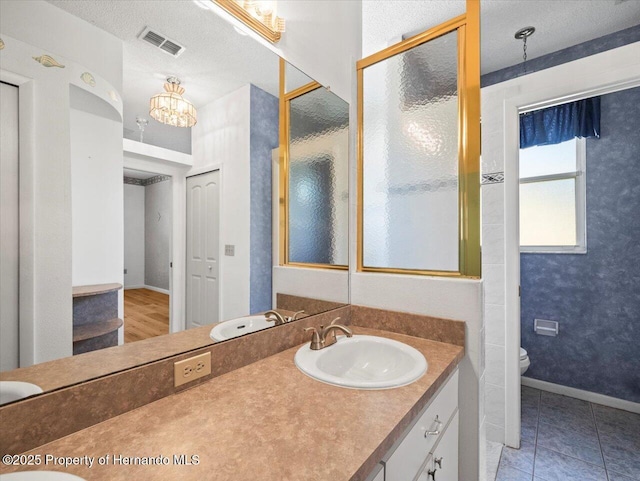 bathroom with visible vents, baseboards, toilet, vanity, and a textured ceiling