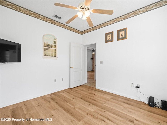 empty room featuring light wood-type flooring, baseboards, visible vents, and a ceiling fan