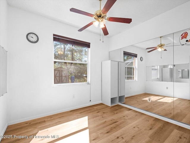 unfurnished bedroom featuring multiple windows, wood finished floors, and baseboards