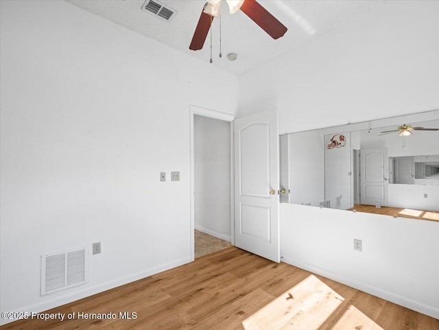 empty room with ceiling fan, wood finished floors, visible vents, and baseboards