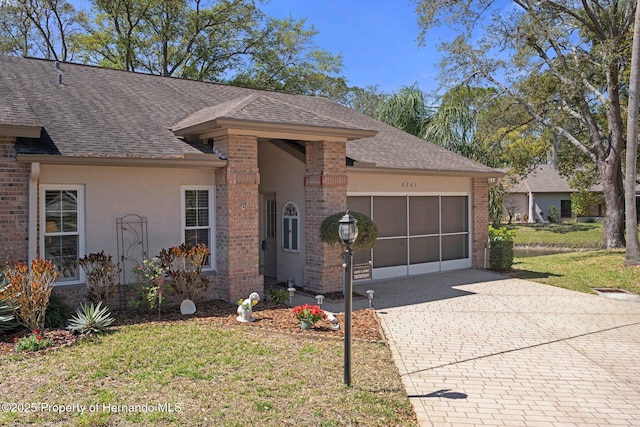 single story home featuring decorative driveway, brick siding, a garage, and roof with shingles