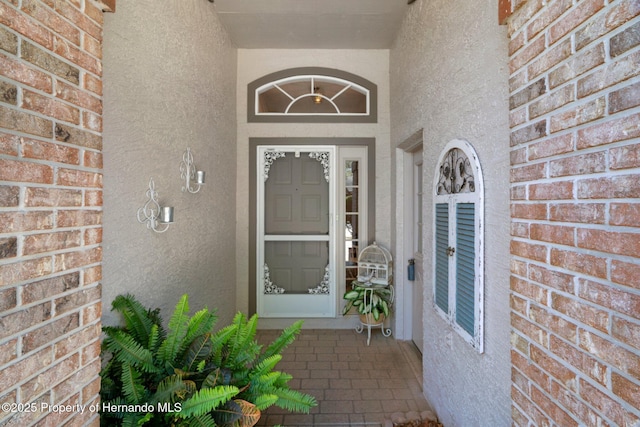 doorway to property with brick siding and stucco siding