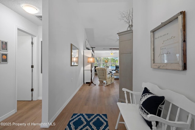 corridor with visible vents, baseboards, and light wood-style floors