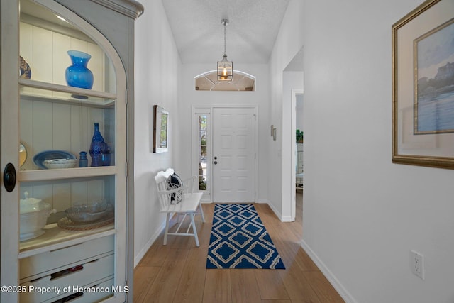 foyer featuring a textured ceiling, baseboards, and wood finished floors