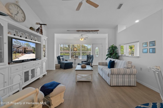 living room with a ceiling fan, visible vents, wood finished floors, and baseboards