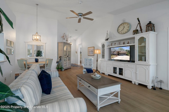 living room featuring ceiling fan, baseboards, high vaulted ceiling, and wood finished floors