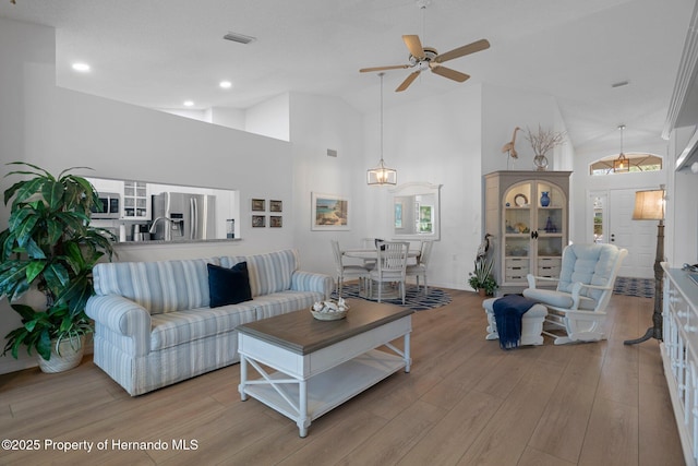 living area with recessed lighting, high vaulted ceiling, a ceiling fan, and light wood finished floors