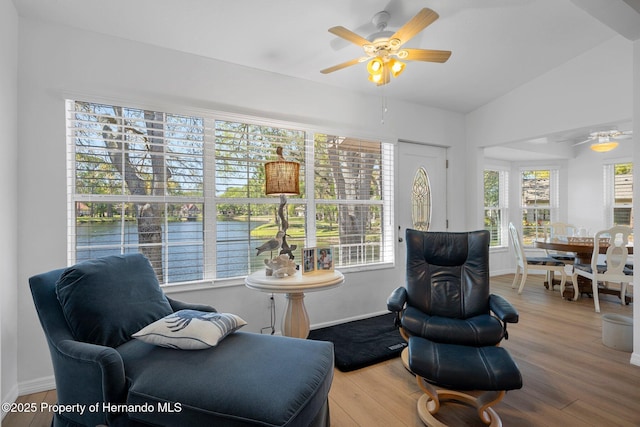 living area featuring baseboards, wood finished floors, and vaulted ceiling