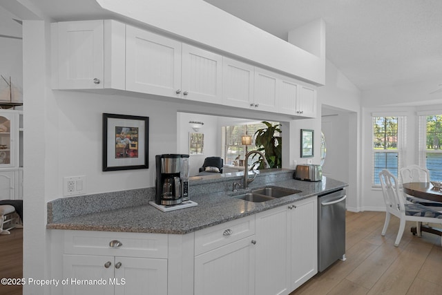 kitchen with light wood finished floors, white cabinetry, stone countertops, a sink, and dishwasher