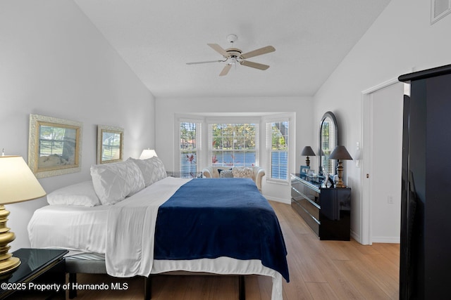 bedroom featuring visible vents, baseboards, vaulted ceiling, light wood-style floors, and a ceiling fan