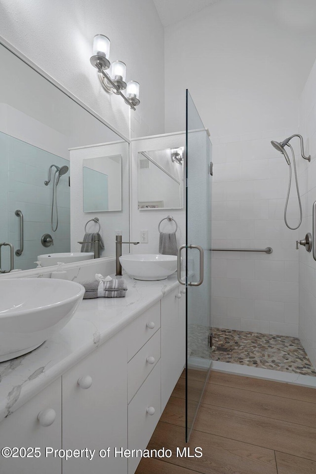 bathroom featuring a sink, double vanity, and a shower stall