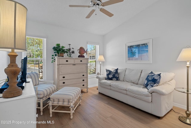 living room featuring baseboards, lofted ceiling, light wood-style floors, and a ceiling fan