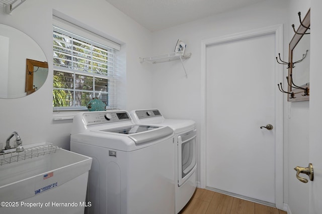 washroom featuring a sink, light wood-style floors, laundry area, and washer and clothes dryer