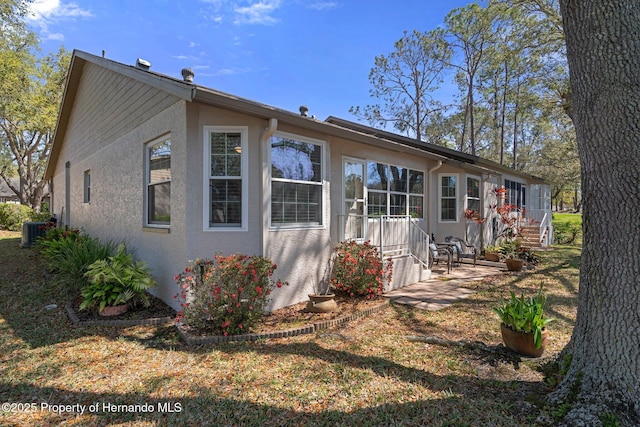 rear view of property featuring central AC unit and stucco siding