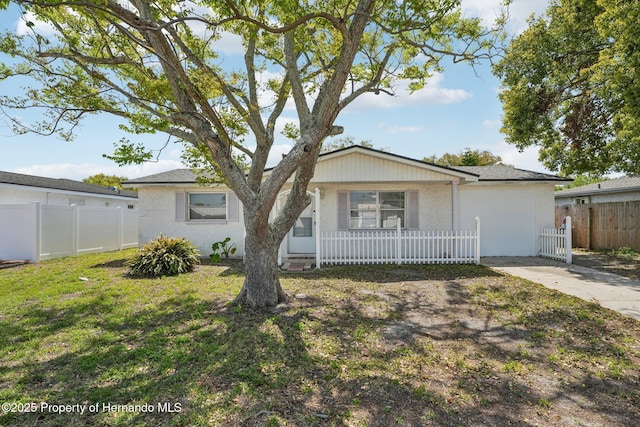 ranch-style home featuring stucco siding, a porch, a front yard, and fence