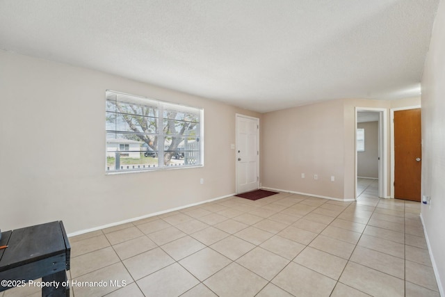 unfurnished living room featuring light tile patterned floors, baseboards, and a textured ceiling