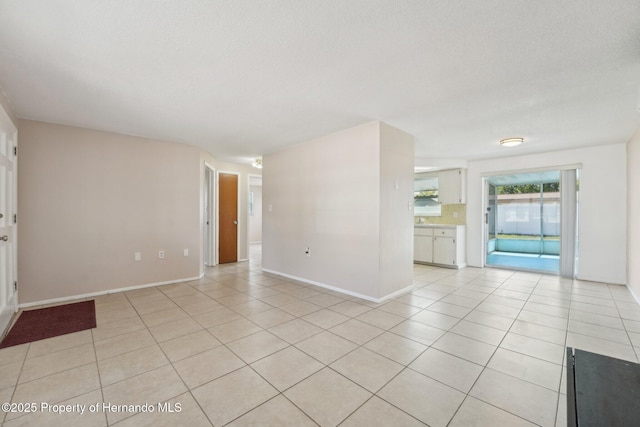 unfurnished living room with light tile patterned floors, baseboards, and a textured ceiling