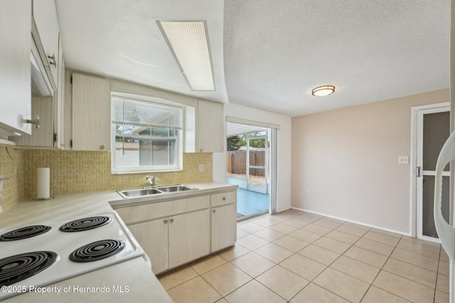 kitchen featuring a sink, tasteful backsplash, light tile patterned flooring, and light countertops