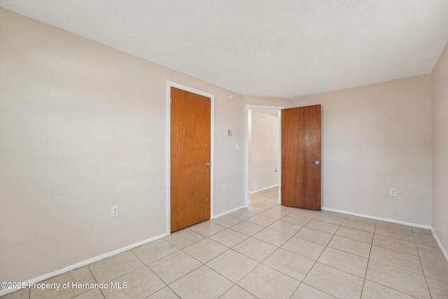 unfurnished room with light tile patterned flooring and baseboards