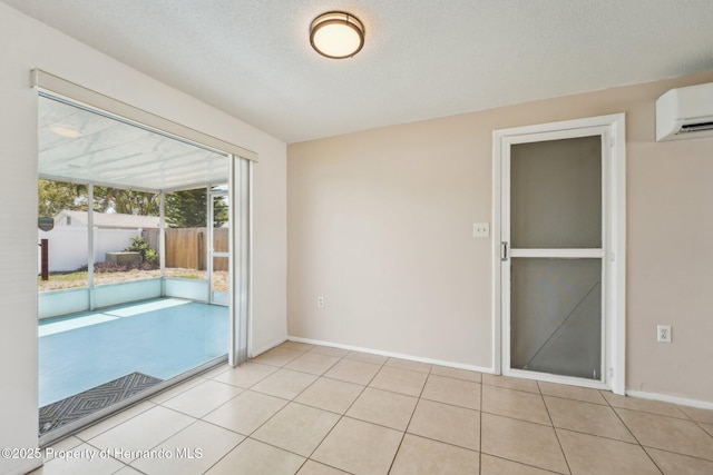 spare room featuring tile patterned floors, baseboards, a textured ceiling, and an AC wall unit