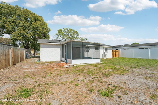 rear view of property with a yard, a fenced backyard, stucco siding, and a sunroom