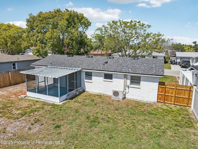 back of house with roof with shingles, a yard, a fenced backyard, a sunroom, and ac unit