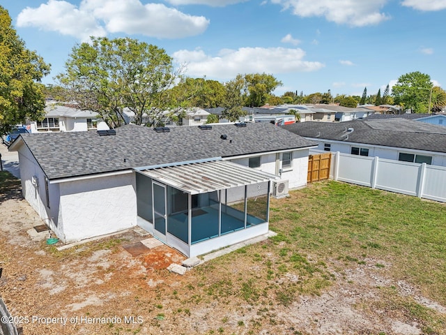 back of property featuring a shingled roof, fence, a yard, a residential view, and a sunroom