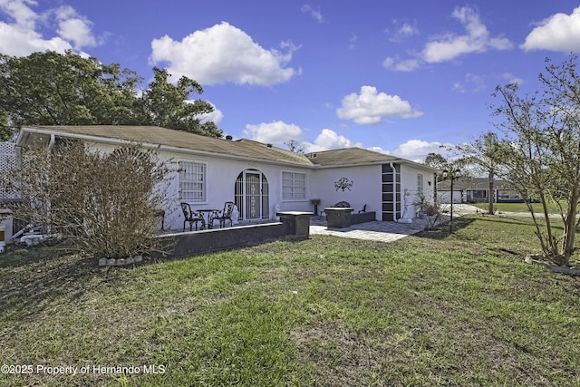 rear view of property with a patio area, a lawn, and stucco siding