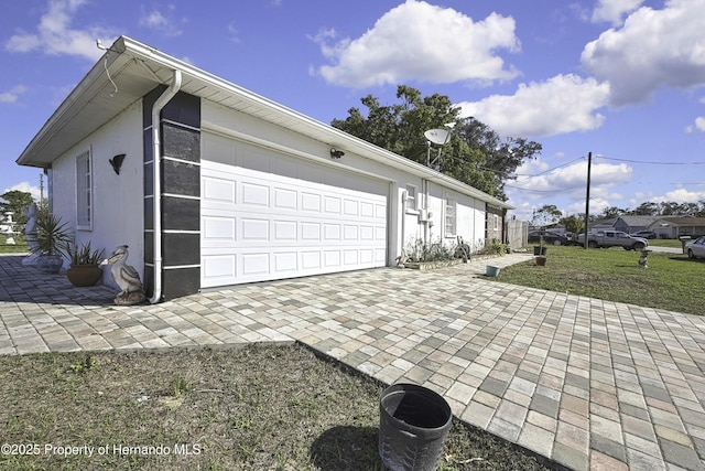 exterior space with stucco siding, an attached garage, and a front yard