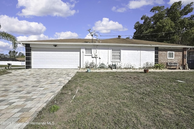 view of front of property with a front lawn, decorative driveway, an attached garage, and stucco siding