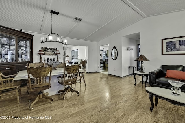 dining room featuring visible vents, baseboards, lofted ceiling, an inviting chandelier, and wood finished floors