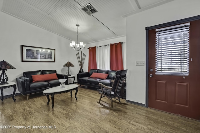 living area featuring visible vents, baseboards, a notable chandelier, and wood finished floors