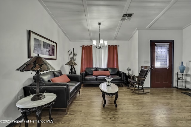 living room featuring wood finished floors, visible vents, and a chandelier