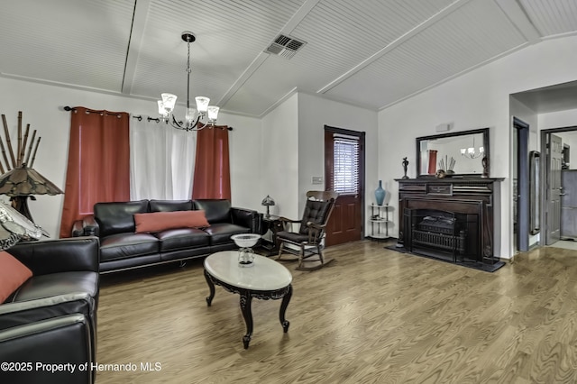 living room with visible vents, lofted ceiling, a fireplace, an inviting chandelier, and wood finished floors