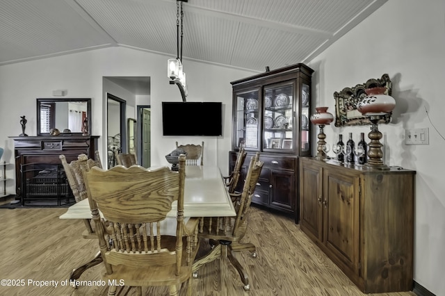 dining space featuring light wood finished floors and lofted ceiling