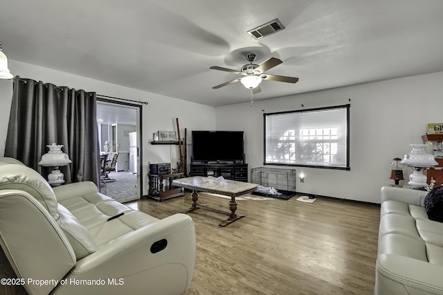 living area with visible vents, a ceiling fan, and wood finished floors